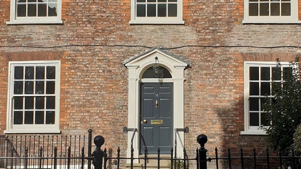 A brick building with a gated entrance, multiple windows, and a central door with a decorative arch. - 14 St Saviours Place, YORK (York)
