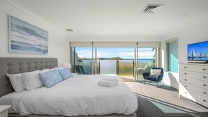 Quarto com uma cama grande, televisão e vista para o mar.