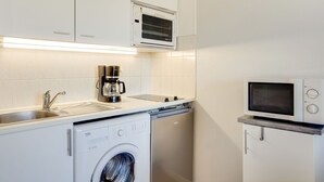 A compact kitchen with a washing machine, a coffee maker, and a microwave. - Nice apartment for 4 guests with WIFI, TV, balcony and pets allowed (Cabourg)