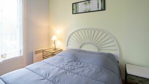 A bedroom with a bed, a nightstand, a lamp, a wall-mounted picture, and a window. - Lovely apartment for 4 people with WIFI, TV and balcony (Cabourg)