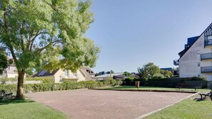 A courtyard with a paved area, surrounded by grass and trees. - Lovely apartment for 4 people with WIFI, TV and balcony (Cabourg)