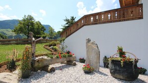 A garden with a wooden fence, a white wall, and a mountainous landscape in the background.