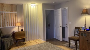 Ein Zimmer mit einer hölzernen Bank, einer Lampe, einer Tür und einem Schrank.