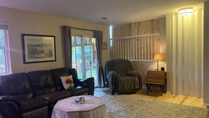 Ein Wohnzimmer mit einer Ledersofa, einem runden Couchtisch, einem abgedeckten Sessel und einer Lampe.