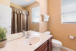 A bathroom with a double sink, a toilet, and a mirror.