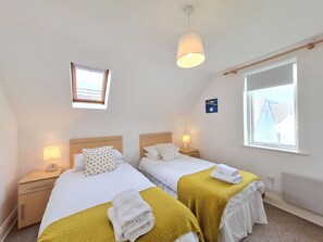 Ein Hotelzimmer mit zwei Betten, einem Fenster, einer Lampe und einem kleinen Bild an der Wand.