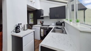 Una cocina compacta con tragaluz, horno empotrado y microondas.