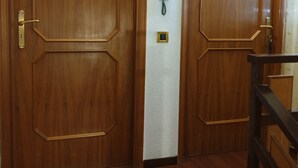 Une porte en bois avec une plaque nominative, un téléphone fixé au mur et un petit coffre-fort.