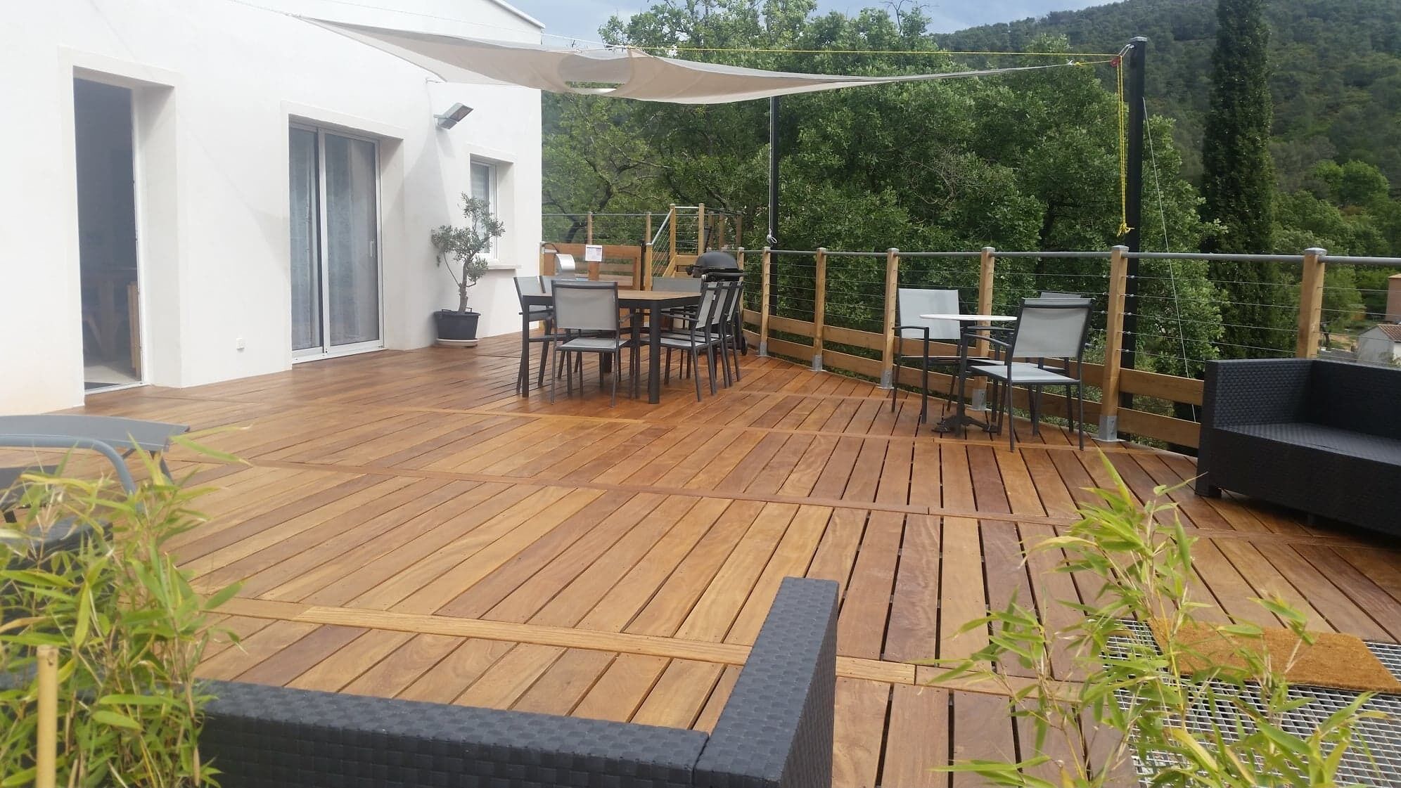 A wooden deck with outdoor furniture, including a table and chairs, and a sofa.