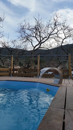 Una piscina al aire libre de temporada, sombrillas