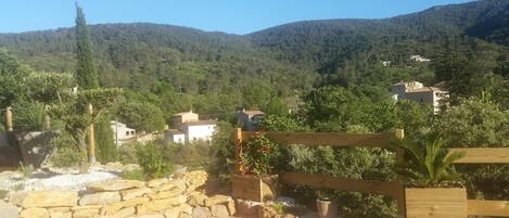 Paisaje rural con muros de piedra, cercas de madera y casas rodeadas de vegetación y colinas.