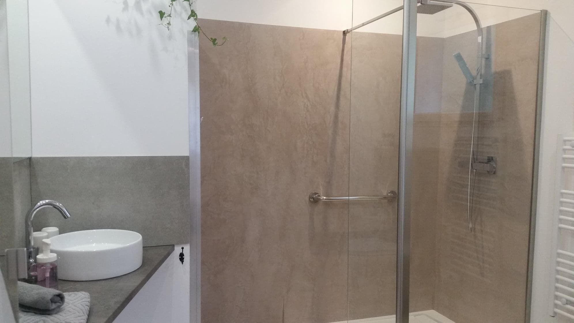 A modern bathroom with a glass-enclosed shower, a white sink, and a towel.