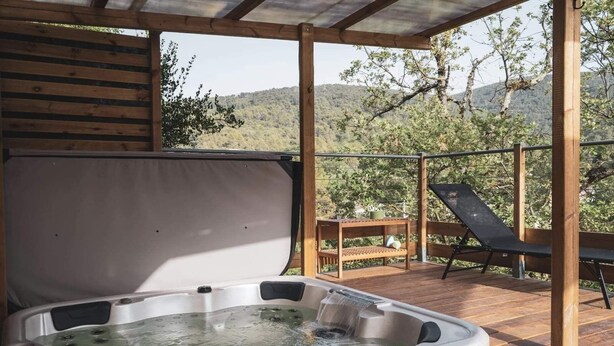A hot tub on a wooden deck with a view of trees and hills. - Les chambres de Toucas (Sollies-Toucas)