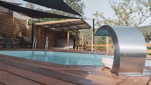 A swimming pool with a modern water feature, wooden deck, and lounge chairs. - Les chambres de Toucas (Sollies-Toucas)