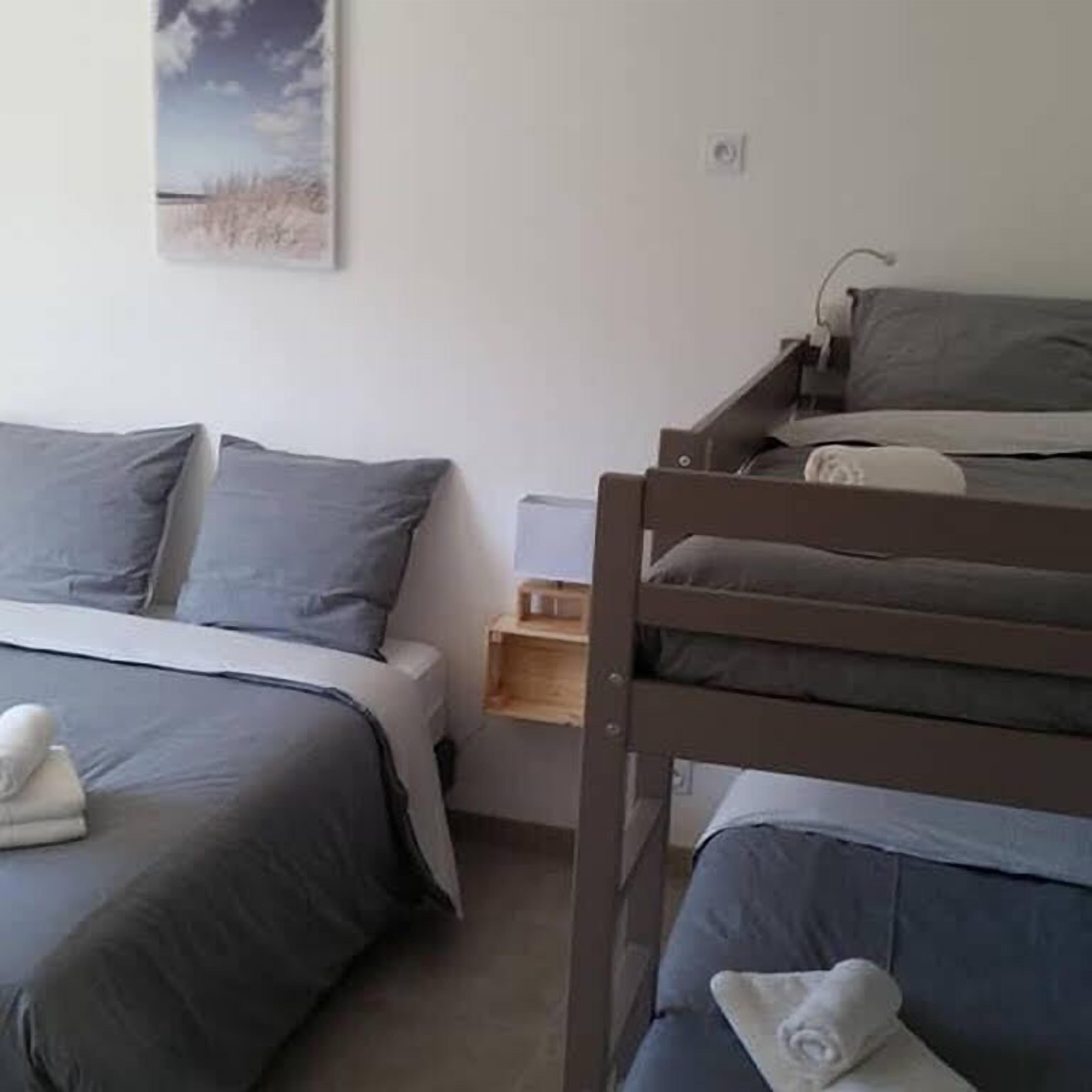 Un dormitorio con una cama individual, una cama litera y una mesita de noche con lámpara.