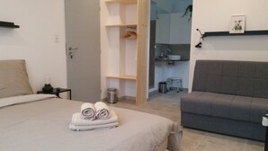 A bedroom with a bed, a grey sofa, a bedside table, and a small stool. - Les chambres de Toucas (Sollies-Toucas)