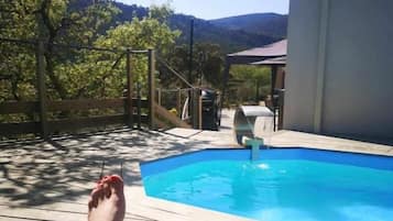 A poolside area with a wooden deck, a lounge chair, and a glass of wine.