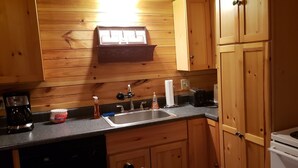 Una cocina con armarios de madera, un lavamanos, una cafetera, un tostador y una estufa.