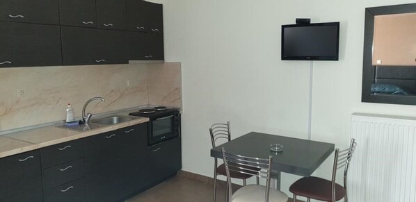 Une cuisine compacte avec un coin repas, un téléviseur à écran plat fixé au mur et une fenêtre donnant sur un beau paysage.