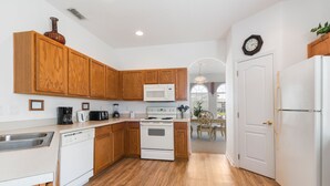 A kitchen with wooden cabinets, a white stove, and a microwave. - Villa Dodes by VillaDirect (Clermont)
