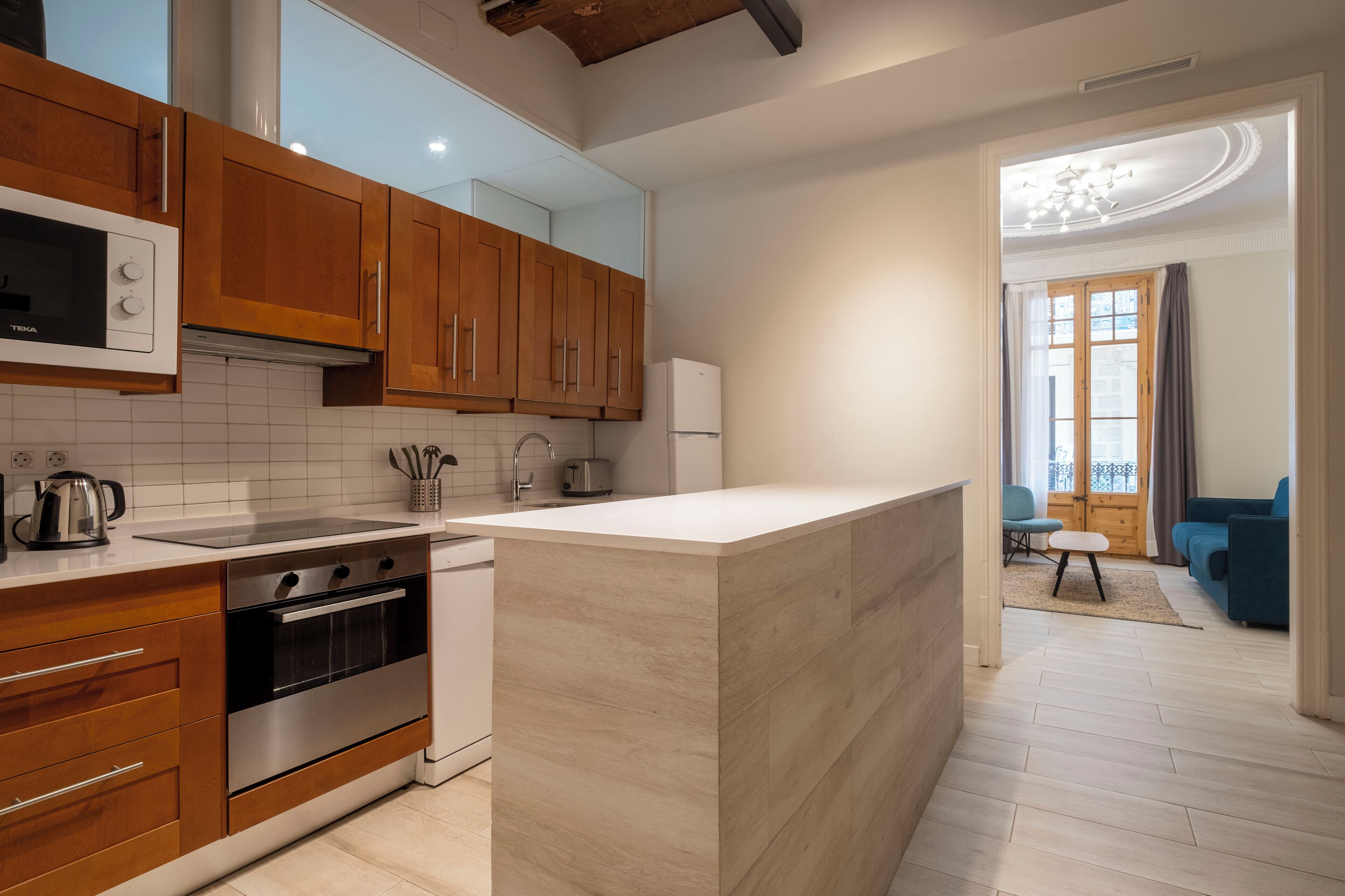 A modern kitchen with wooden cabinets, a built-in oven, and a white countertop.