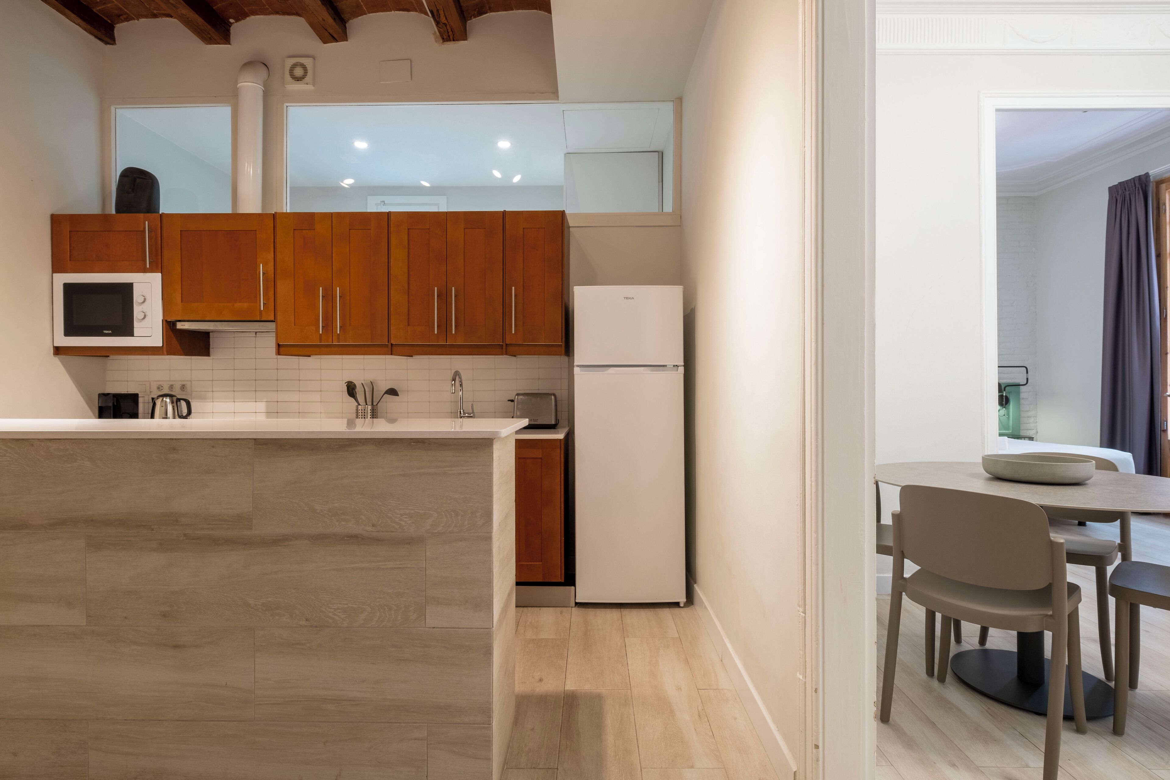 Una cocina moderna con armarios de madera, microondas, tostadora y refrigerador.