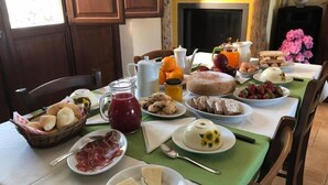 Une table de petit-déjeuner avec divers aliments, une carafe de jus et un vase décoratif rempli de fleurs.