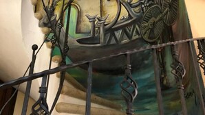 Un escalier orné d’une fresque représentant une voiture et un vélo d’époque.