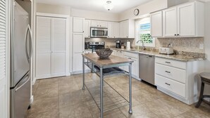 A kitchen with white cabinets, stainless steel appliances, a granite countertop, and a tiled floor. - Top‘s Naples Park Home, sleeps 6 adults + toddlers, close to beach, near all! (Naples)