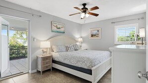 A bedroom with a bed, nightstands, a ceiling fan, a window with blinds, and a door leading to a balcony. - Top‘s Naples Park Home, sleeps 6 adults + toddlers, close to beach, near all! (Naples)