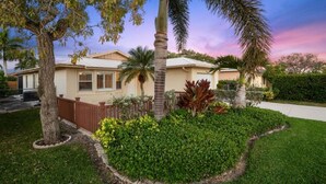 A residential house with a well-maintained lawn, a wooden fence, and a variety of plants. - Top‘s Naples Park Home, sleeps 6 adults + toddlers, close to beach, near all! (Naples)