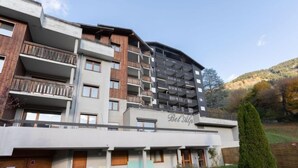 Ein mehrstöckiges Hotel mit Balkonen und Fenstern, einem Schild mit der Aufschrift "Bel' Alp" und einem gepflegten Garten.