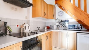 Eine Küche mit Holzausstattung, einem schwarzen Backofen, einer Mikrowelle und einer Holztreppe.