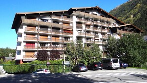 Ein mehrstöckiges Hotel mit Balkonen, einem Parkplatz und einer Bergkulisse.