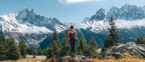 Una persona parada sobre un afloramiento rocoso, con montañas al fondo.