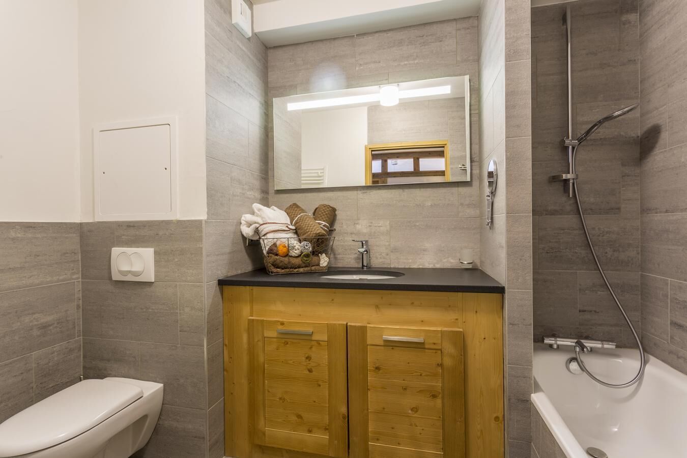 A bathroom with a wooden vanity, a toilet, a bathtub, and a shower.