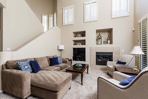 A living room with a beige sofa, a coffee table, a fireplace, and a staircase. - Reduced Rates Just Posted! Cachet Condo (Scottsdale)