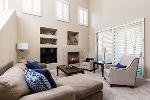 A living room with a fireplace, beige sofas, armchairs, and a TV. - Reduced Rates Just Posted! Cachet Condo (Scottsdale)