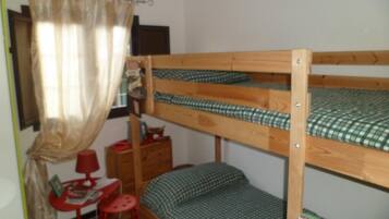 A bunk bed room with a small table and chair, a red lamp, and a curtain.