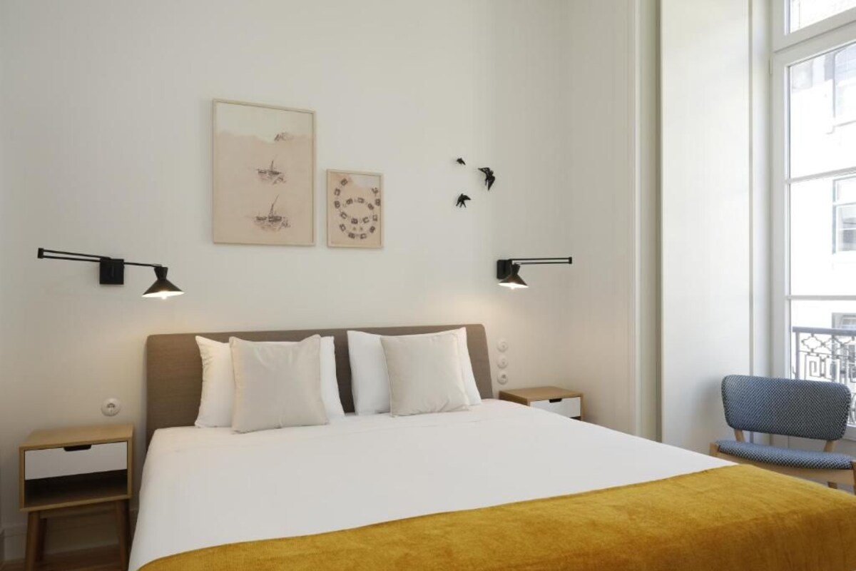 Habitación de hotel con cama, mesitas de noche, decoración en la pared y ventana con vistas.