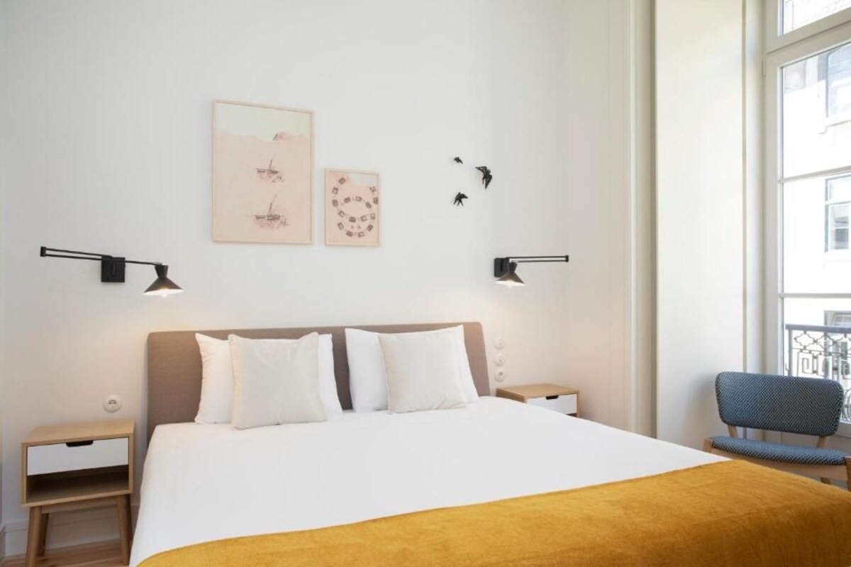 A neatly arranged hotel room with a large bed, bedside tables, a chair, and artwork on the walls.