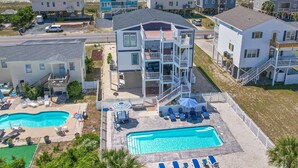 A beachfront property with multiple buildings, a swimming pool, and outdoor seating areas. - "A Penny From Heaven" 2nd row luxury 4 bedroom with pool (Holden Beach)