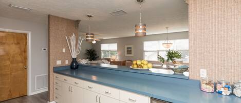 Een keuken met een blauw aanrecht, witte kasten en hangende pendelverlichting.