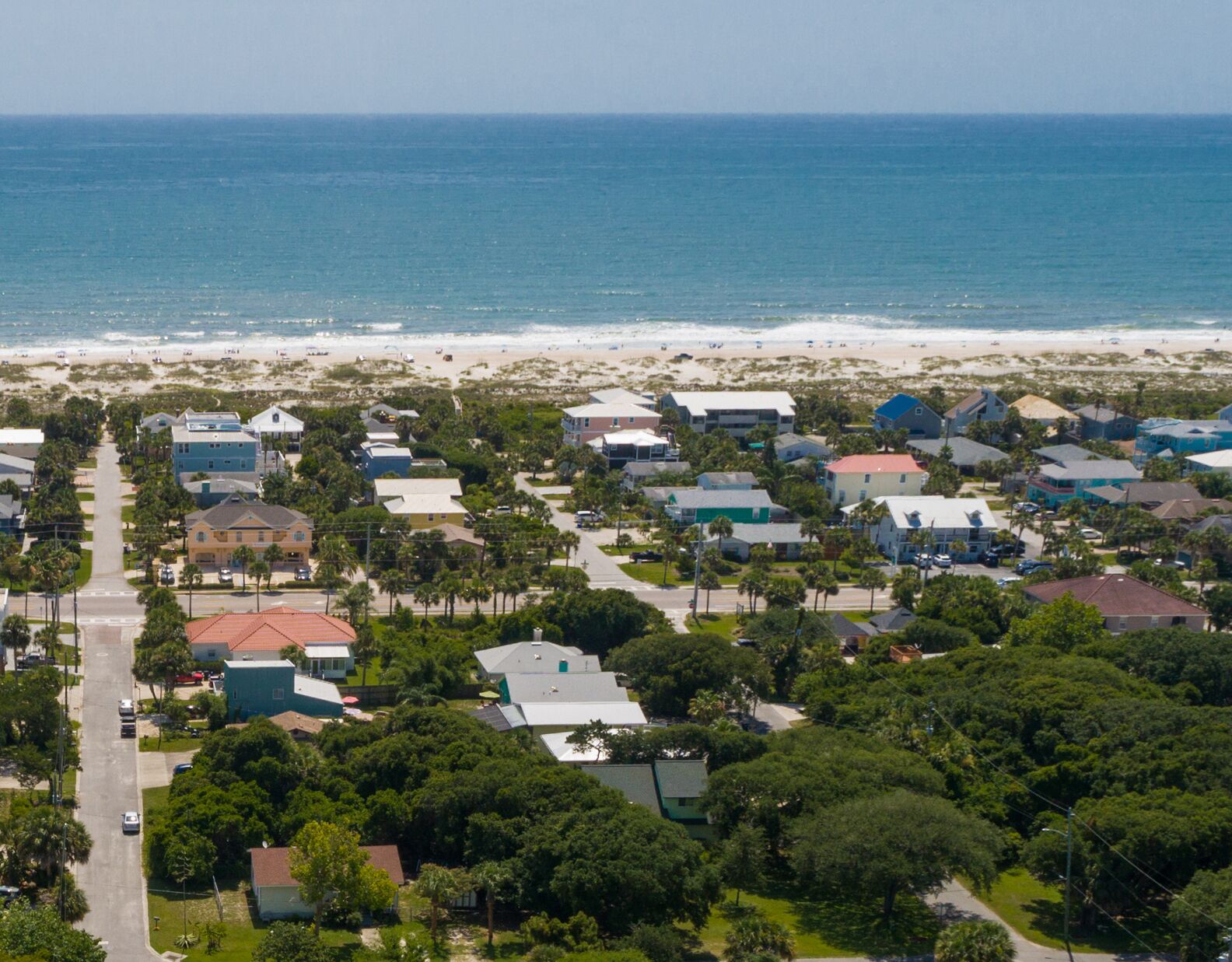 A coastal residential area with houses and a beach in the background.