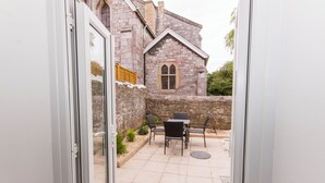 A patio with a table and chairs, a stone wall, and a building with a stone facade and a window. - Admiralty street by Pureserviced (Plymouth)