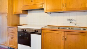 A kitchen with wooden cabinets, a stove, and a sink. - Cosy apartment in villa for 7 people with pool, WIFI, TV and pets allowed (Bucine)