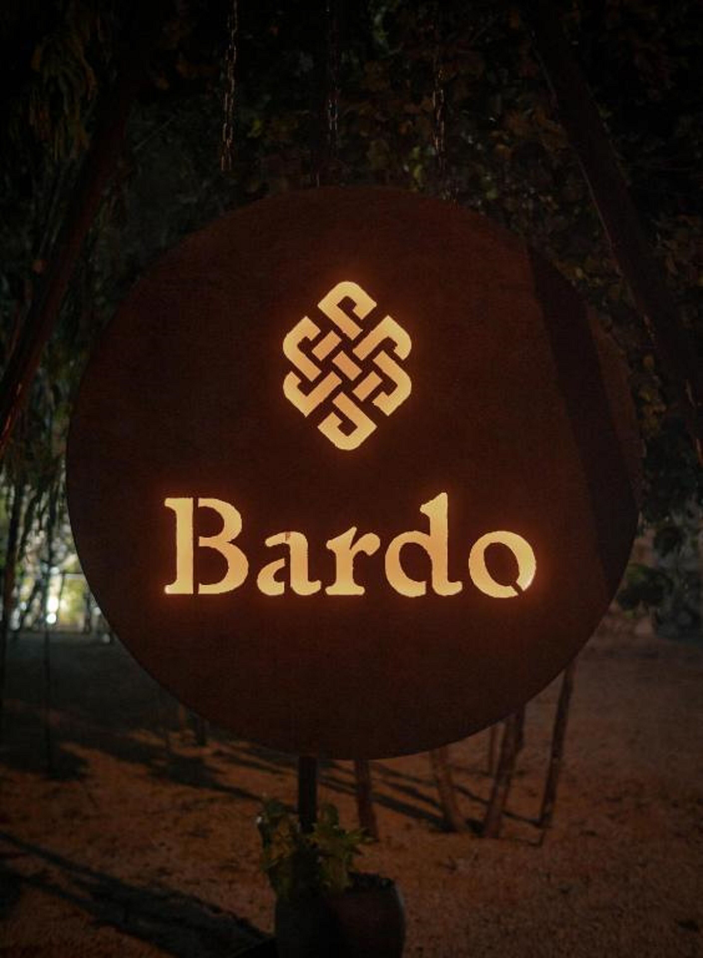 Un letrero con el nombre "Bardo" iluminado en letras doradas, que presenta un diseño de nudo decorativo sobre el texto.