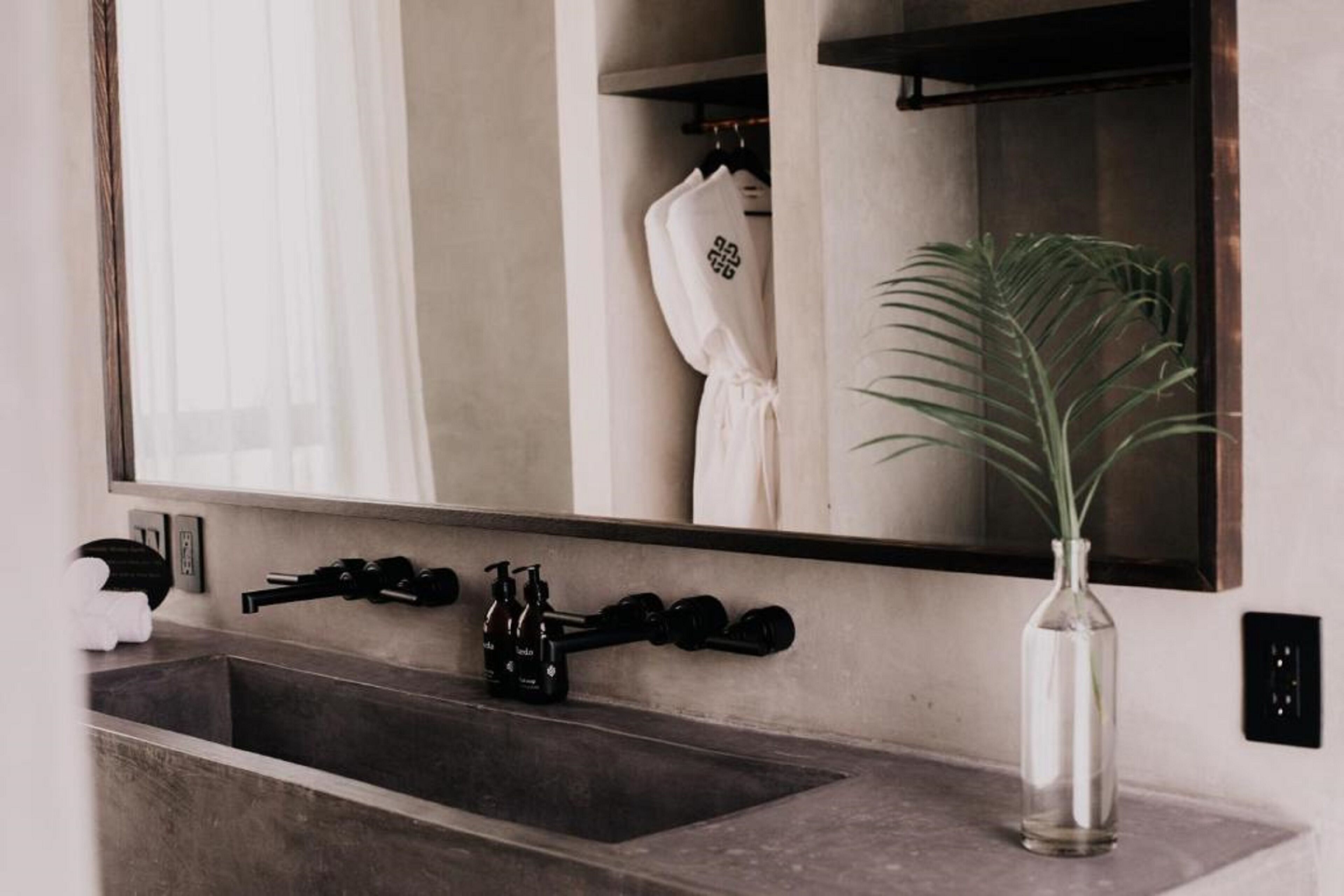 A bathroom with a large mirror, a sink with a towel rack, and a potted plant.