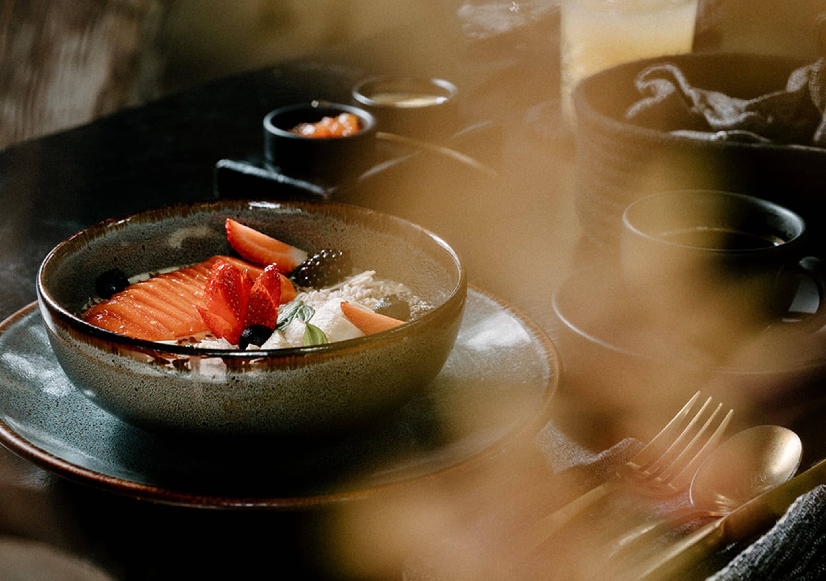 A bowl of food with strawberries and a spoon on a plate.