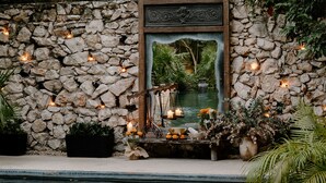 A stone wall with a decorative wooden frame and a small pond. - Hotel Bardo Adults Only (Tulum)